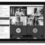 A laptop screen displays a virtual meeting with five visible participants and several others with initials only. A chat window is open on the left, showing messages and shared documents, highlighting the power of unified communications in healthcare teams.