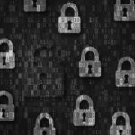A pattern of blue padlock icons on a digital background with binary code; one red, broken open padlock highlights data security risks, symbolizing a cybersecurity breach or vulnerability when working remote.
