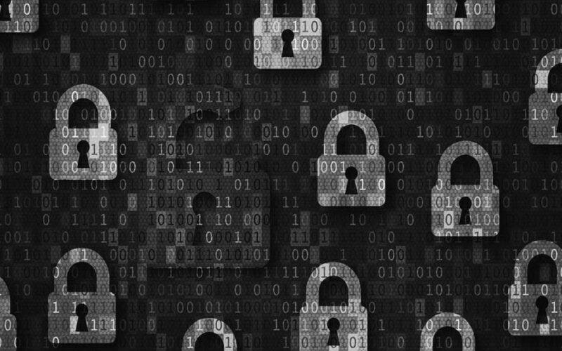 A pattern of blue padlock icons on a digital background with binary code; one red, broken open padlock highlights data security risks, symbolizing a cybersecurity breach or vulnerability when working remote.