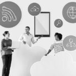 Three people stand among large cloud cutouts, smiling and holding technology-related icons like a tablet and network symbols, representing cloud computing, Unified Communication Services, and digital business connectivity. Blue circular icons float around them.