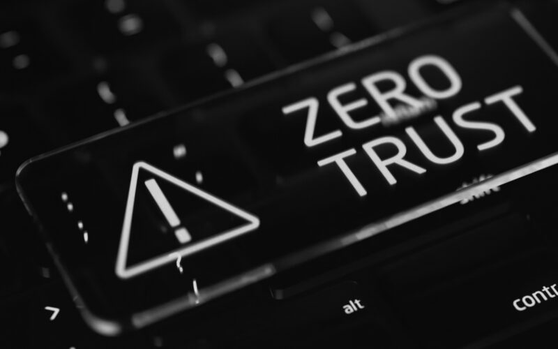 A glowing key with an exclamation mark warning symbol and the words ZERO TRUST sits on a dark computer keyboard, representing network security and the importance of zero trust network security in today’s evolving threat landscape.