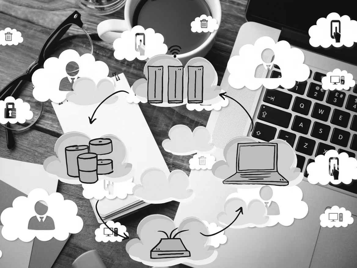 A desk with a laptop, coffee, glasses, and a notebook, overlaid with cloud computing icons—servers, databases, people, and security locks—highlighting data backup and business recovery plan connections.